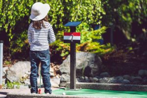 A young girl in Alabama enjoys the outdoors while playing mini golf.
